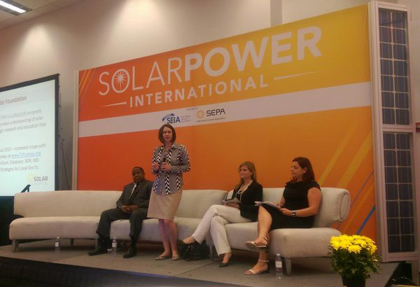 Four women panelists seated on stage at SolarPower International conference with orange backdrop