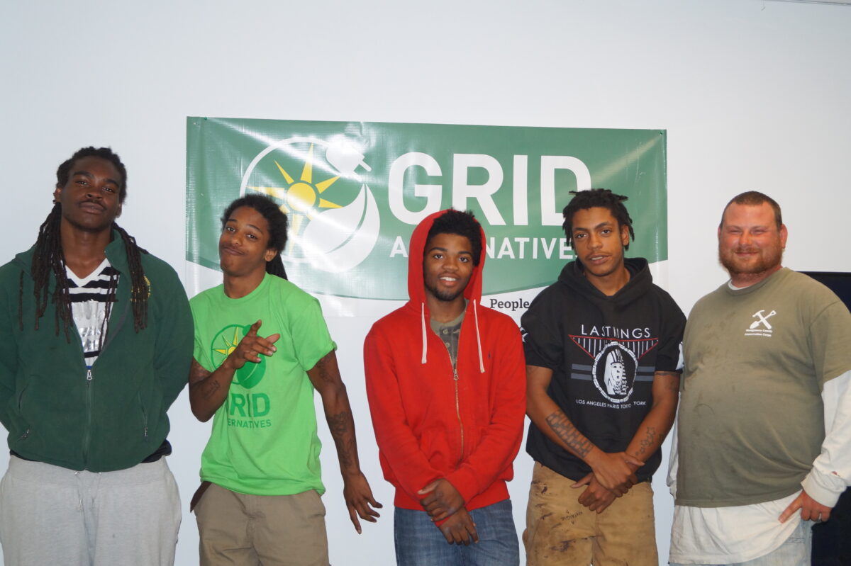 Five people standing in front of a GRID Alternatives banner at an event