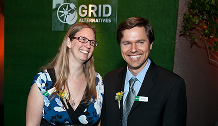Two people smiling at GRID Alternatives event with green banner backdrop