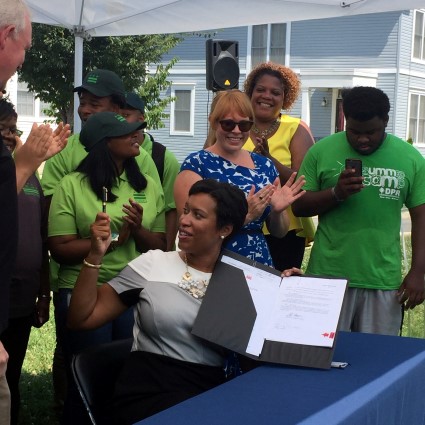 DC Mayor signs Solar4All bill surrounded by community supporters in green shirts