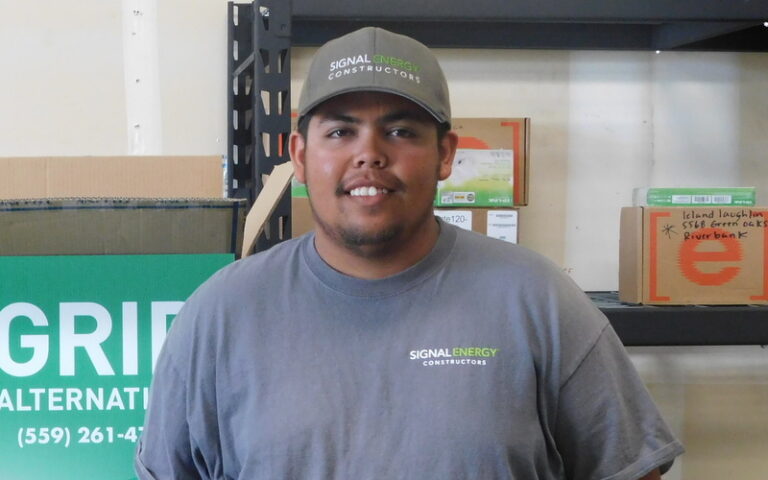 Man wearing Signal Energy Constructors cap and shirt smiling at camera in office setting