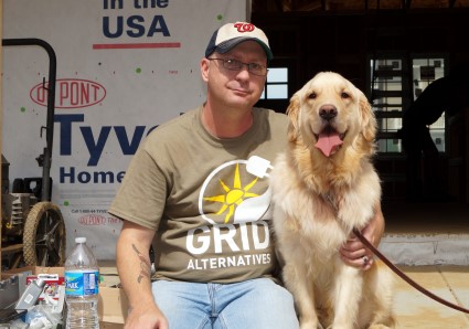 Man in OKIU Alternative t-shirt poses with golden retriever at outdoor event