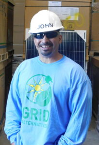 Man named John wearing hard hat and sunglasses at Grid Alternatives warehouse