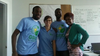 Four team members wearing GRID branded shirts stand together in a classroom setting