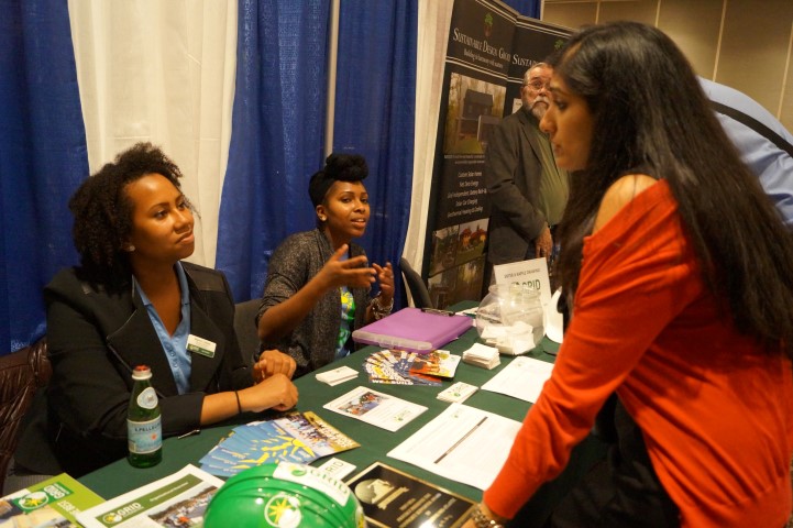 Three women discussing at Solar Focus Job Fair 2016 career expo booth with promotional materials