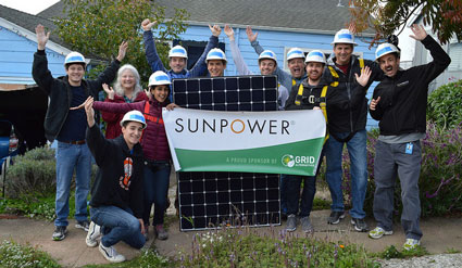 Group of volunteers holding SUNPOWER solar panel banner at community event