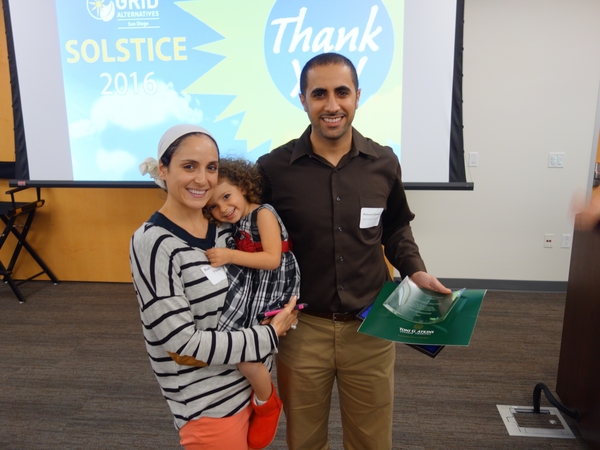 Man holding green certificate with woman and child at Solstice 2016 event