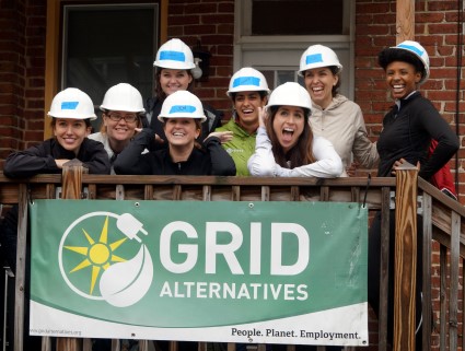 Team of 8 people wearing hard hats holding GRID Alternatives banner with tagline "People. Planet. Employment