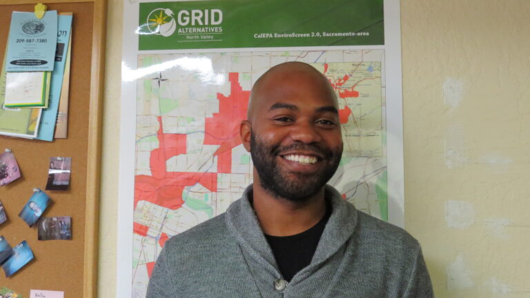 Man smiling in front of GRID Alternatives map showing Sacramento-area solar installation coverage in red