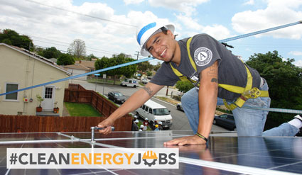 Worker installing solar panel with #CleanEnergyJobs hashtag visible