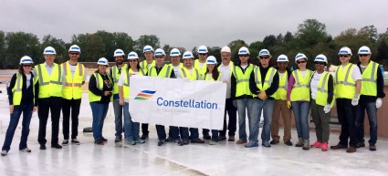 Group of workers in safety vests holding Constellation banner at solar facility groundbreaking