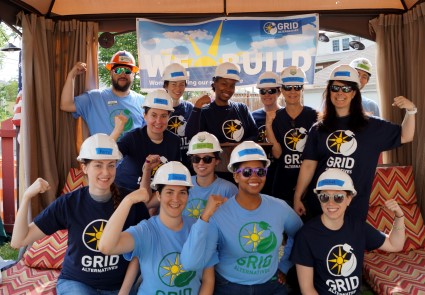 Team of women in GRID shirts and hard hats posing together at a solar energy event