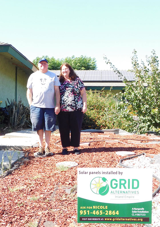 Two people standing in front of a house with solar panels installed, with Grid Alternatives branding and contact information for Nicole displayed