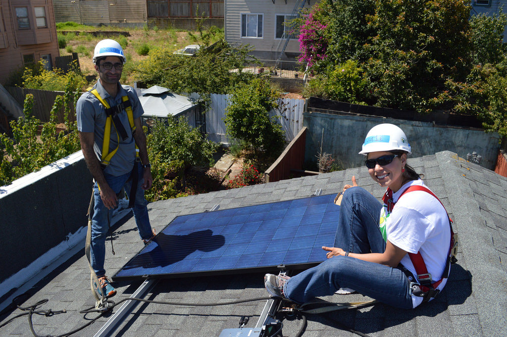 Two workers install solar panels on a residential rooftop in San Francisco