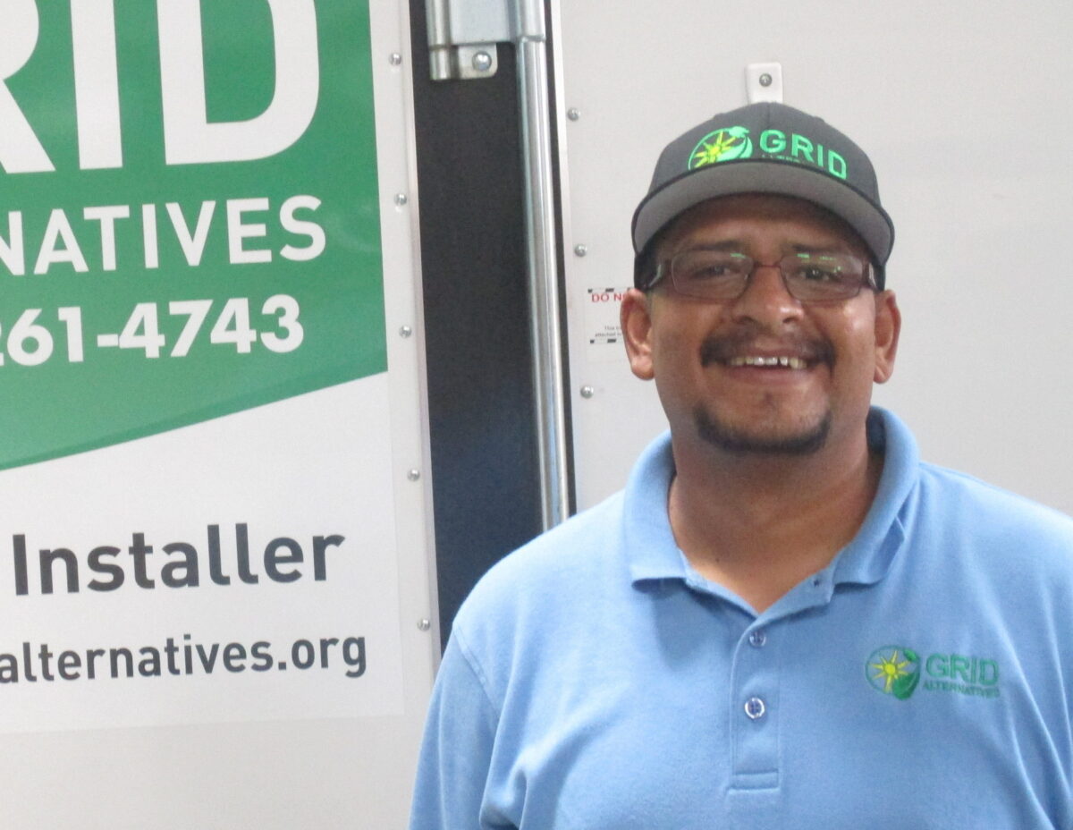 Man in GRID polo shirt smiling in front of GRID Alternatives branded van