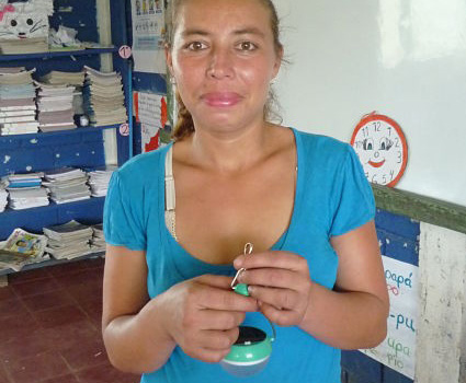 Woman in blue shirt holding a water testing device in a classroom setting