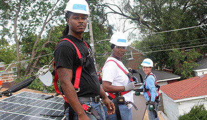 Three workers in safety gear installing solar panels on a residential rooftop in Illinois