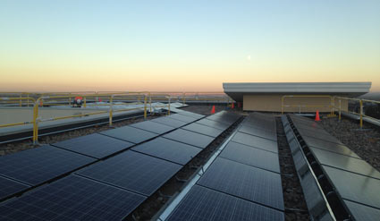 Solar panels on industrial rooftop at sunset with warehouse building visible