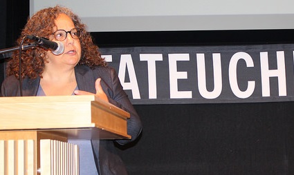 Woman speaking at podium during multifamily conference presentation