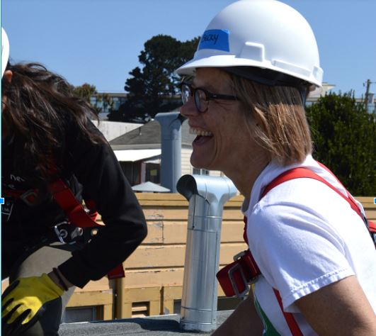 Woman in hard hat and safety vest smiling at construction site