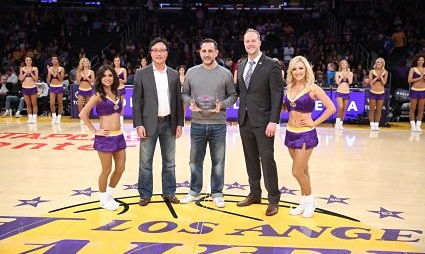 Four men and two cheerleaders stand on Lakers court during accolade ceremony for Michael Kadish