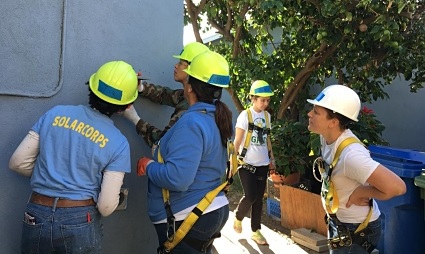Solar installation team in hard hats and safety gear working together on a rooftop project