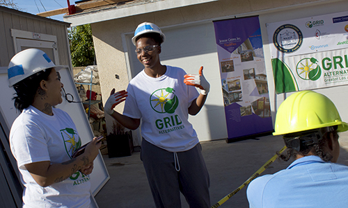 Three women in hard hats and GRIL t-shirts participate in an outdoor community event or training session