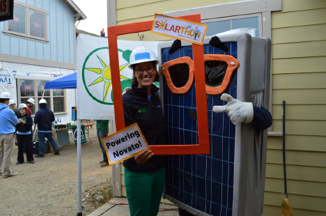 Person in solar panel costume holding "Powering Hawaii" sign at outdoor event