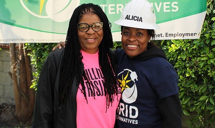 Two women smiling at event with green "Futures" banner and ivy backdrop