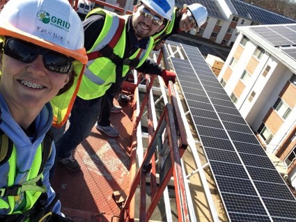 Workers in safety gear installing solar panels on a residential rooftop