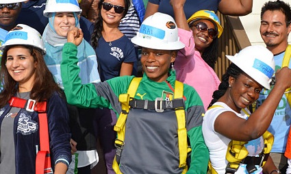 Group of diverse volunteers and staff wearing hard hats and safety vests celebrating GRID Alternatives solar installation milestone