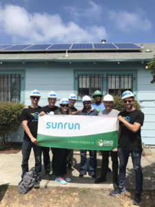 Team holding Sunrun banner in front of house with solar panels installed