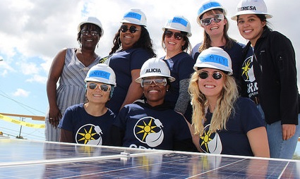 Group of women wearing hard hats and safety glasses at a solar panel installation site