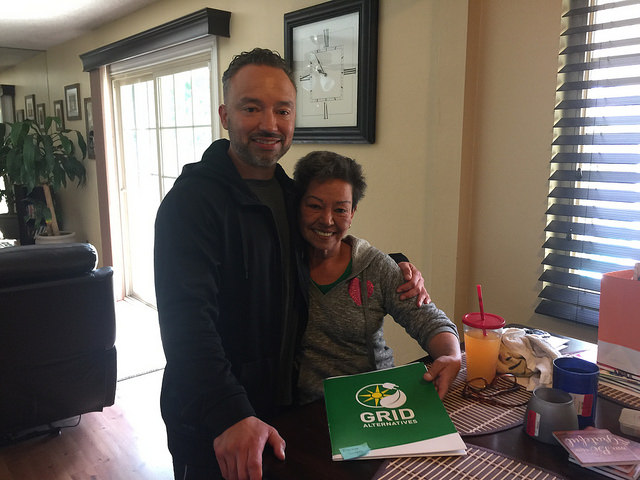 Two people smile together at a table with a Girl Guides box and juice, representing community engagement