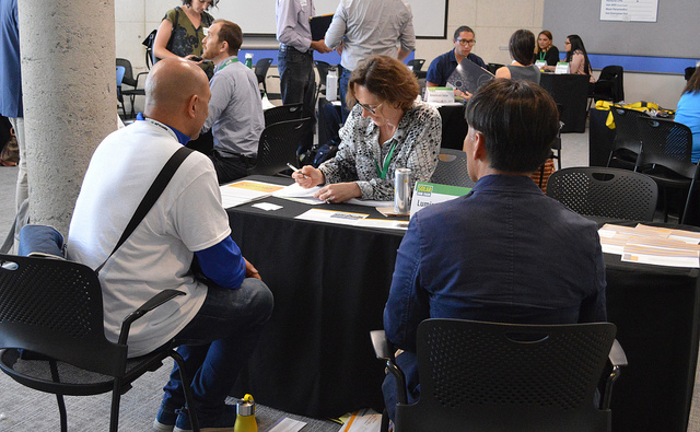 Job seekers meet with recruiters at tables during a summer solar job fair event