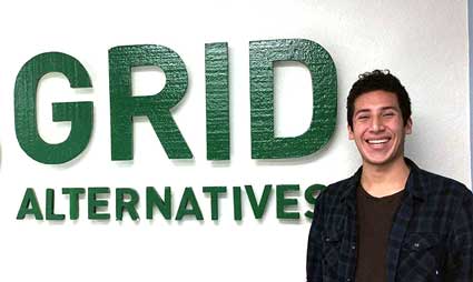 Man smiling next to green "GRID ALTERNATIVES" text on white wall