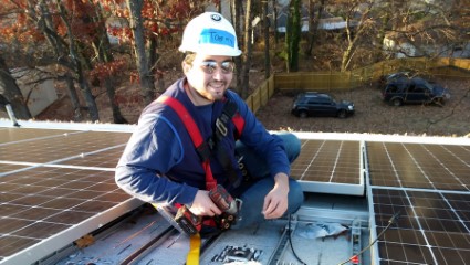 Technician in safety gear working on rooftop solar panel installation