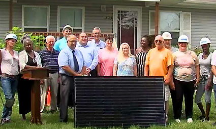 Group of diverse people wearing hard hats standing behind a solar panel in front of a house during job training workshop in Illinois