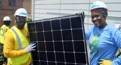 Workers in safety gear installing a solar panel outdoors