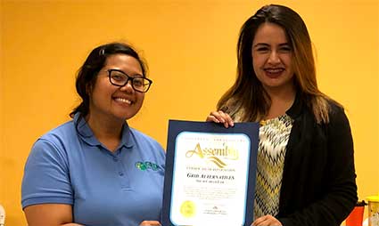 Two women holding a certificate in front of a yellow background at a solar career fair event