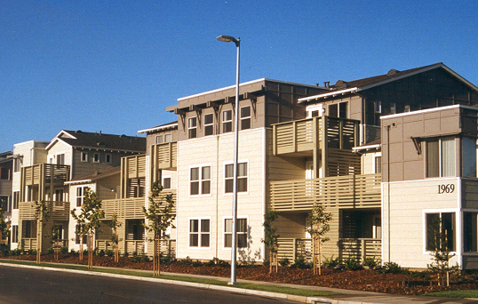 Modern residential buildings with mixed architectural styles in tan, white, and dark colors along a street
