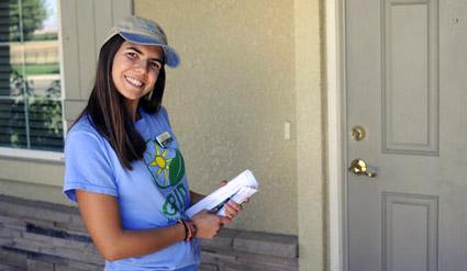 Young woman in blue SolarCorps shirt and cap holding clipboard at front door