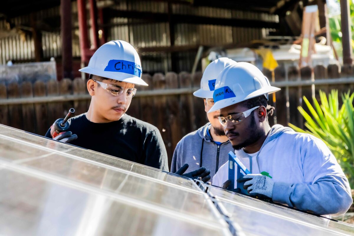 Two construction workers in white hard hats examining blueprints at a job site