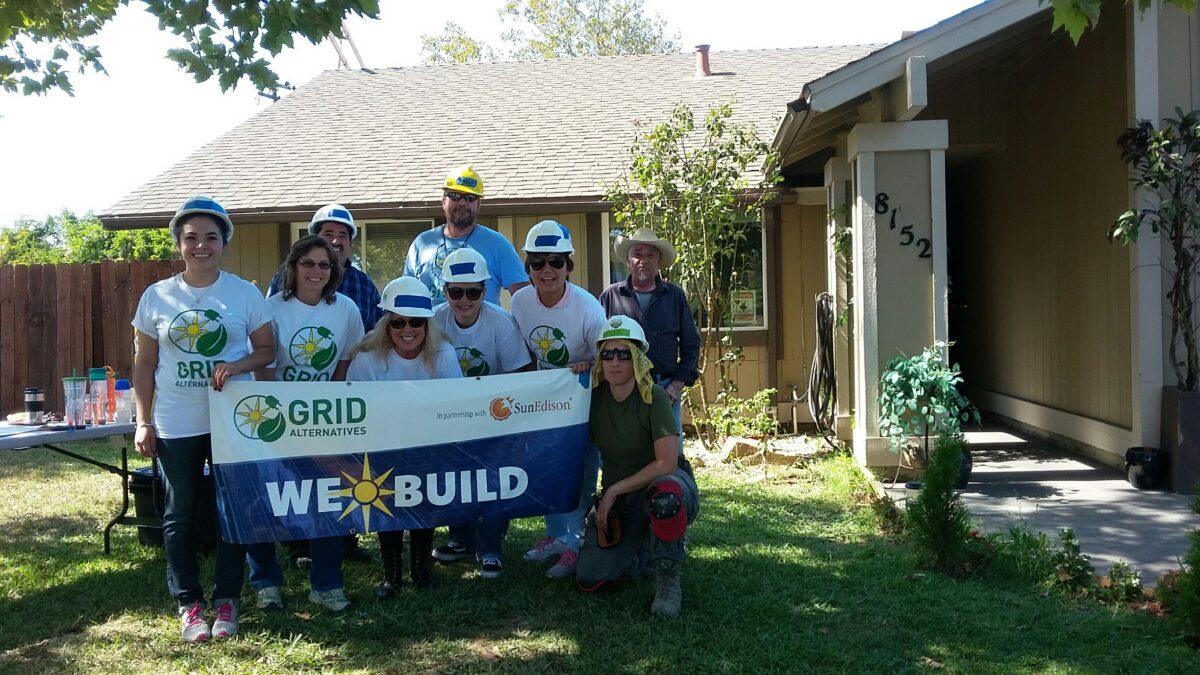 GRID Alternatives volunteer team in hard hats holding "We Build" banner outside home