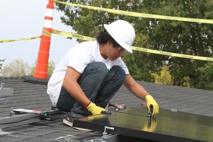A tribal worker in hard hat adjusts panels for the solar PV system