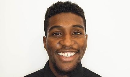 Smiling man with dark curly hair wearing a black shirt against a white background