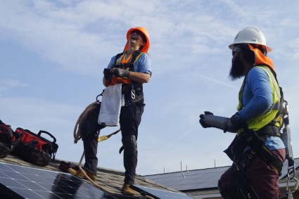 Kaly Moore laughs with her Construction coworker on the roof