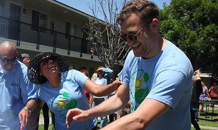 Adults and child playing with water guns outdoors on a sunny day