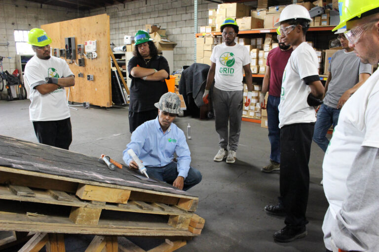 Group training session with GRID participants learning construction skills in warehouse facility