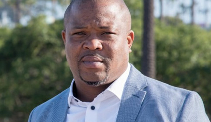 Professional portrait of man in light blue blazer and white shirt outdoors